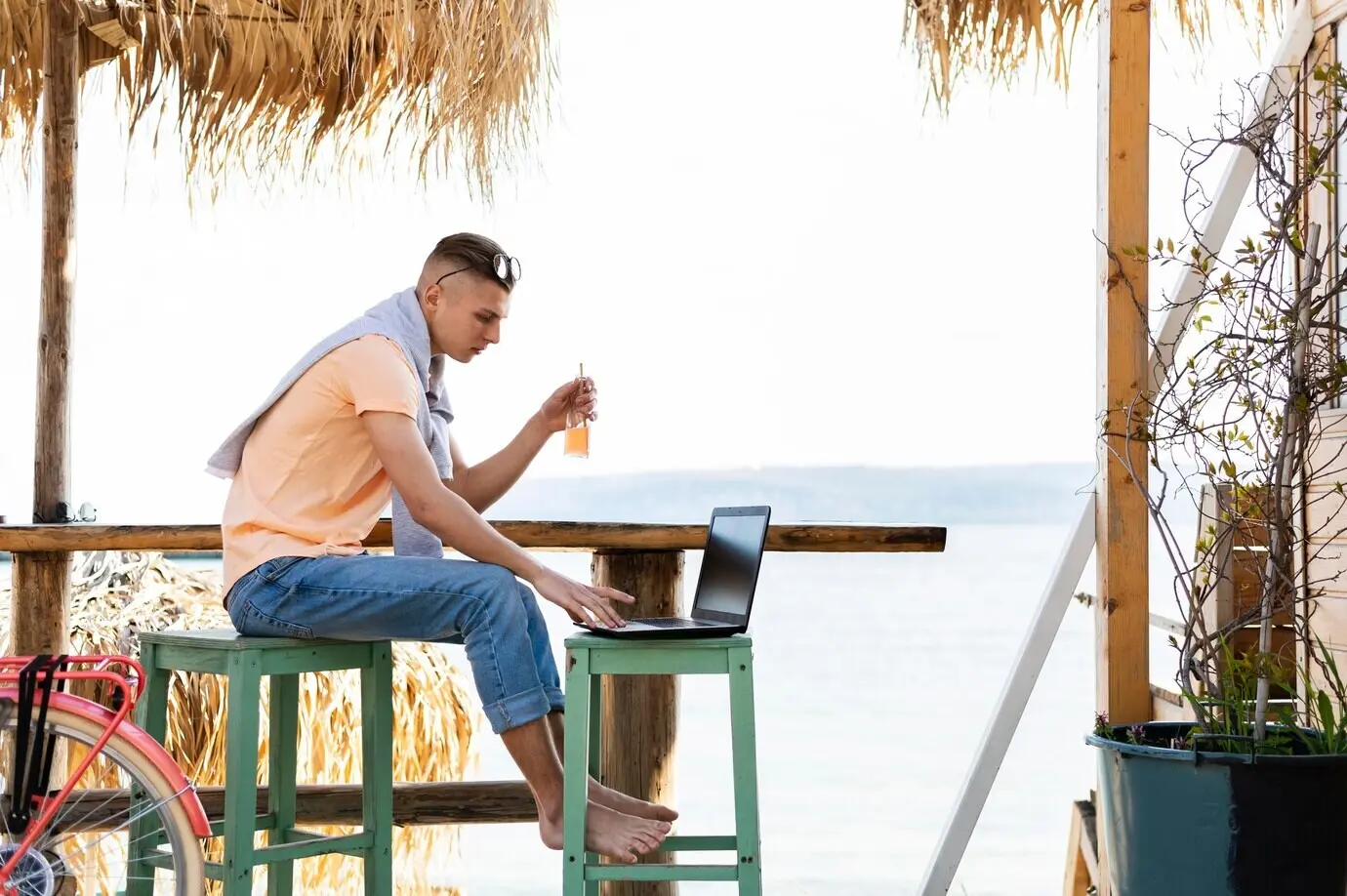 Ganzkörperaufnahme eines Mannes, der im Freien am Laptop arbeitet.